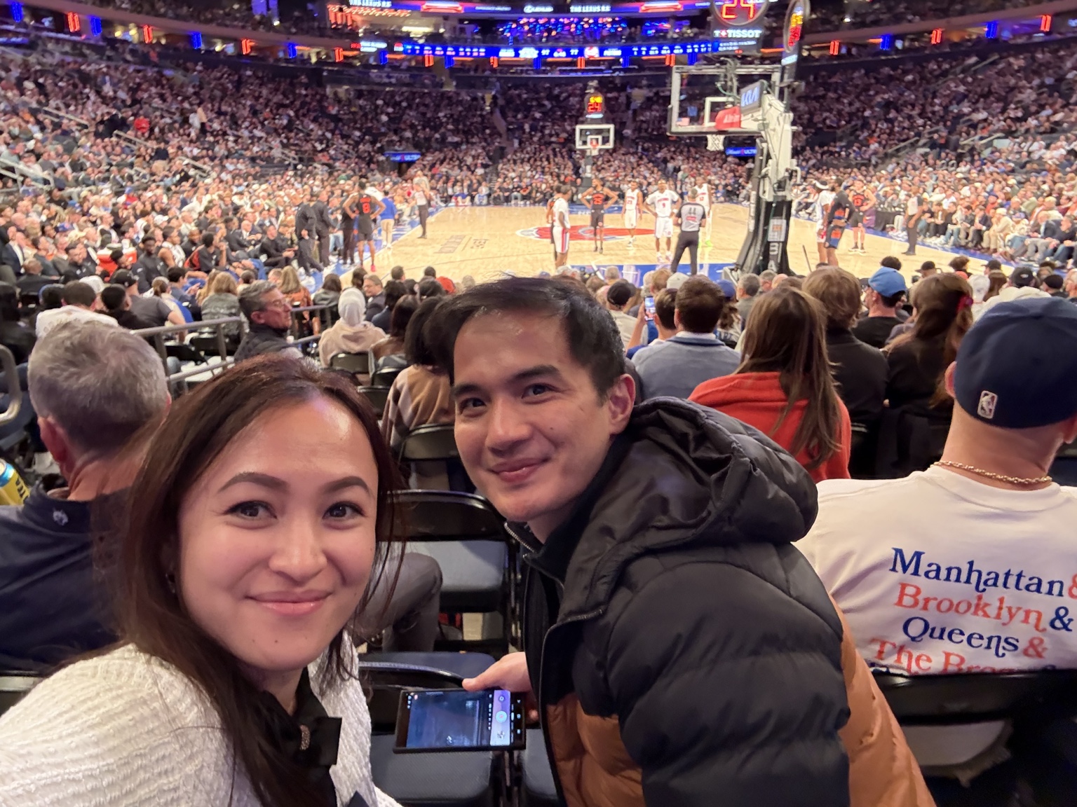 Frances and Francis seated at Madison Square Garden with the court and crowd behind them.