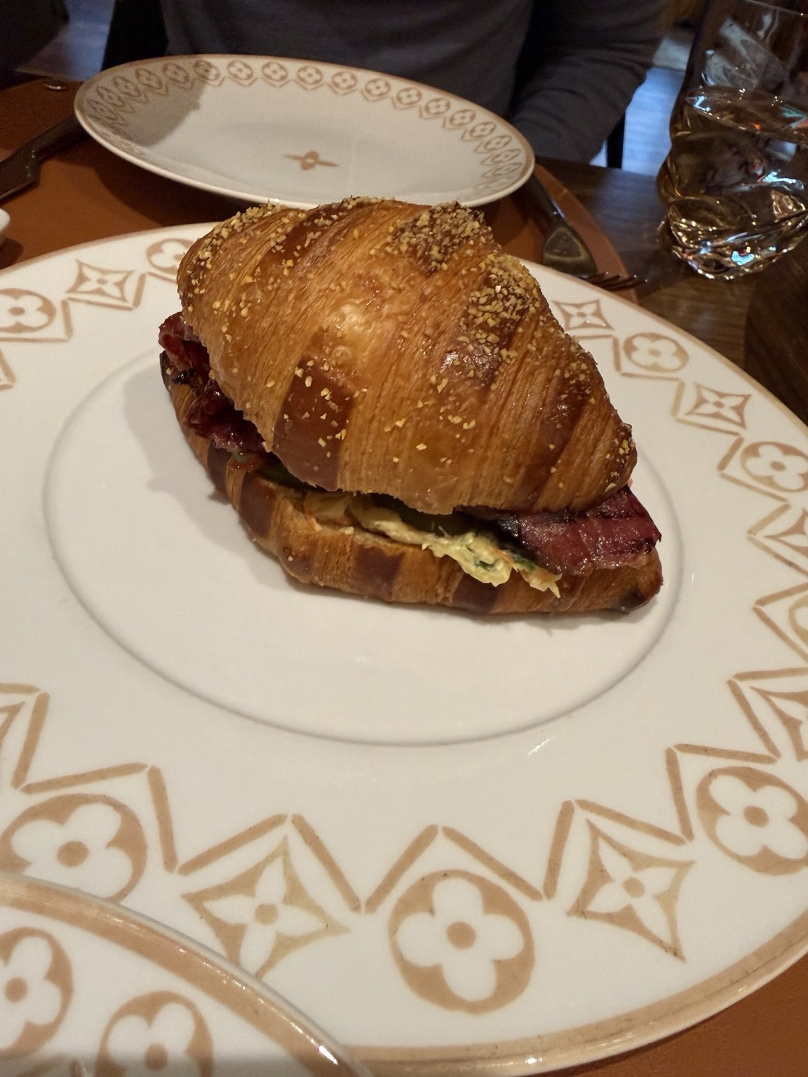 Le Croissant Midtown, filled with wagyu pastrami, on a Louis Vuitton monogrammed plate.